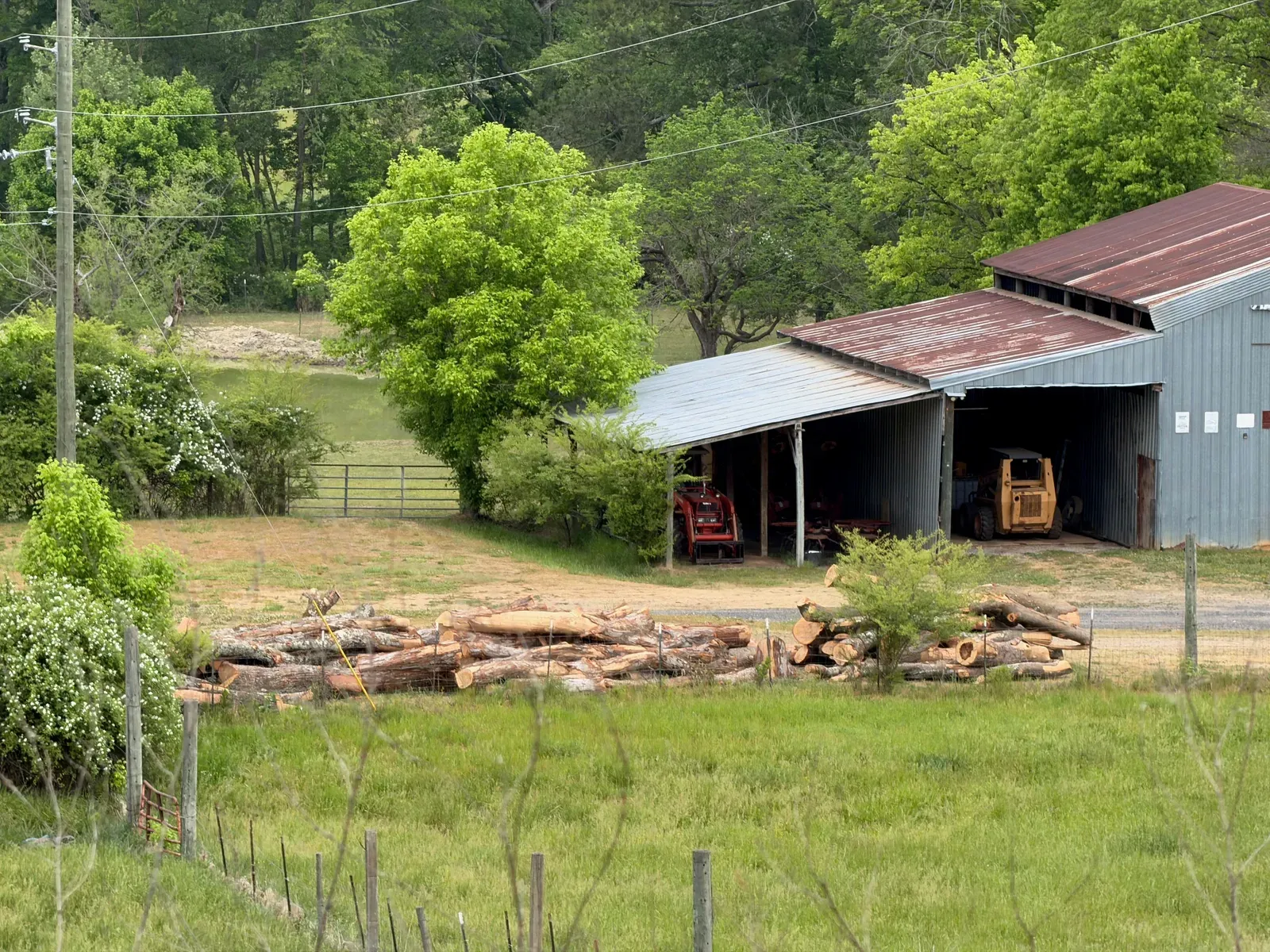 The High School Firewood barn with cut logs stacked in the yard