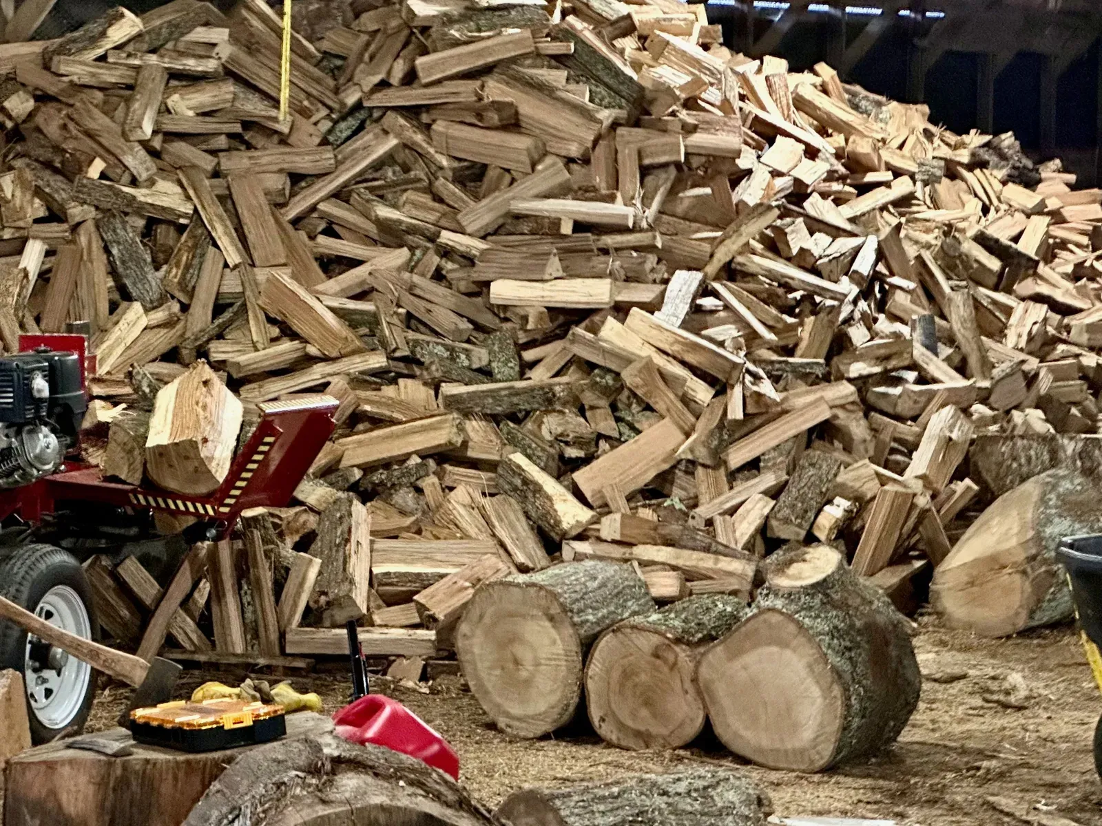 A log splitter in front of a mountain of freshly split firewood