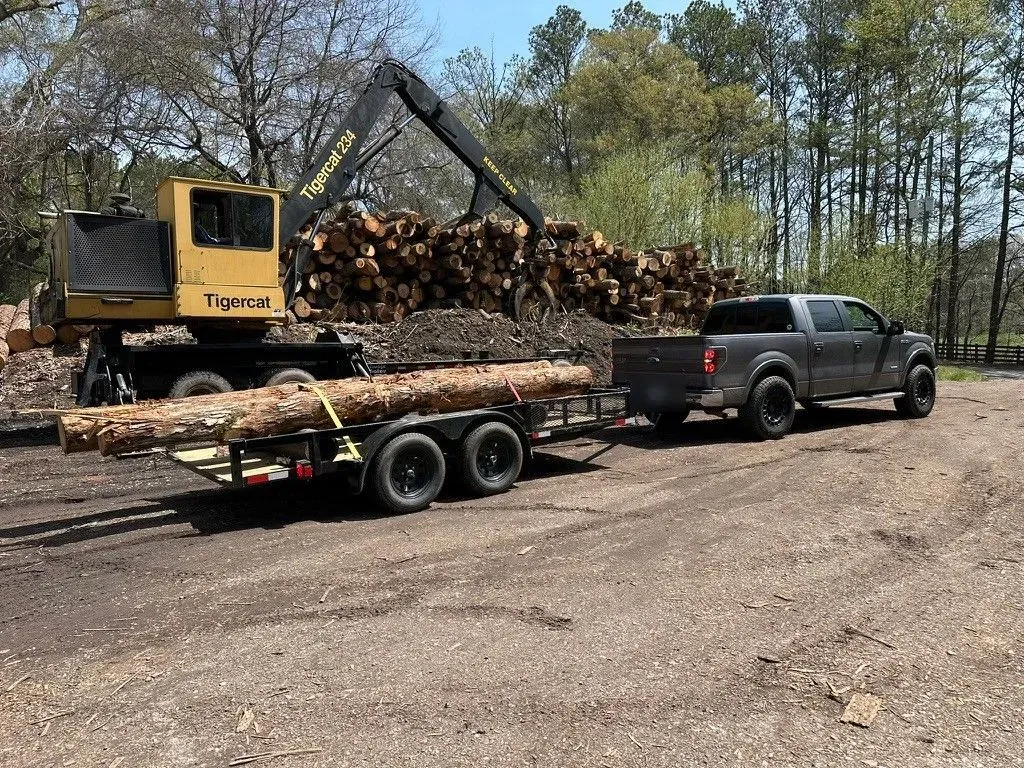 A pickup and trailer hauling logs into the wood yard